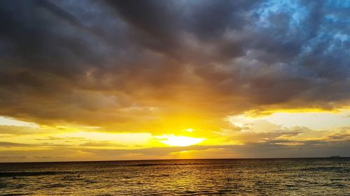 Scenic view of sea against dramatic sky during sunset