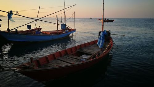 Fishing boat moored in sea against sky