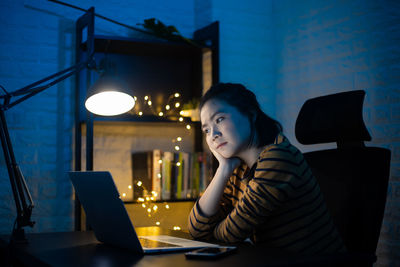 Full length of woman using phone while sitting on table