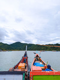 Fishing boats moored on sea against sky