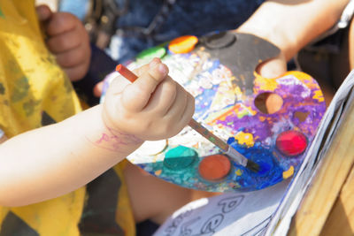 Midsection of child holding multi colored baby