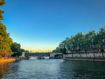 Bridge over river in city against clear blue sky