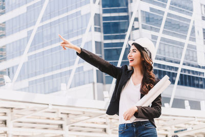 Young woman standing against wall in city