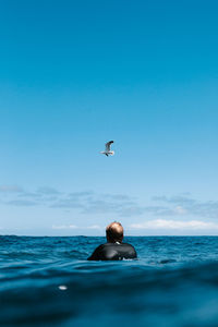 Man swimming in sea against blue sky