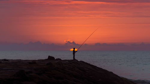 Silhouette of man fishing in sea