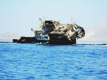 Abandoned boat in sea against clear sky