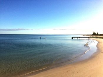 Scenic view of beach against clear blue sky