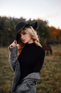 Young woman wearing hat standing on field