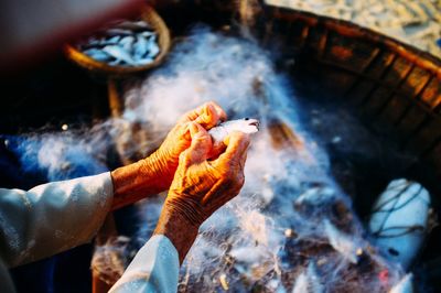 Cropped image of hand holding fish on boat