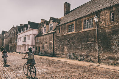 Man riding bicycle on street amidst buildings in city