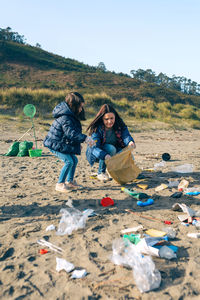 Mother and daughter picking garbage at beach