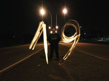 Man with light trails on street at night