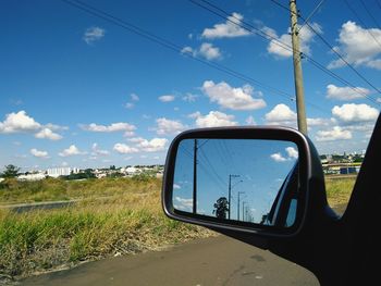 Reflection on side-view mirror of car on road