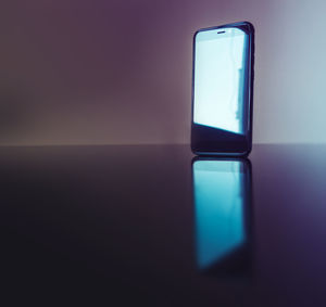 Close-up of illuminated lamp on table against wall