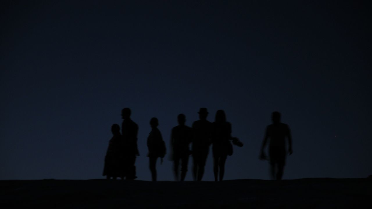 SILHOUETTE PEOPLE STANDING ON FIELD AGAINST SKY DURING SUNSET