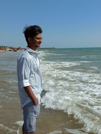 Woman standing on beach against clear sky