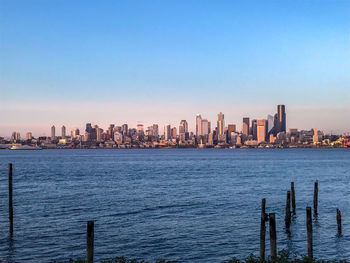 Sea and buildings in city against clear sky