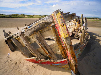 Shipwreck on shore at beach against sky