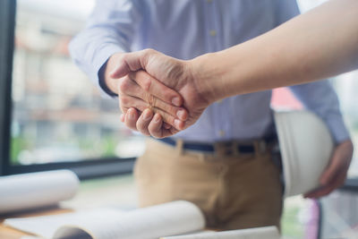 Cropped image of business people giving handshake at office