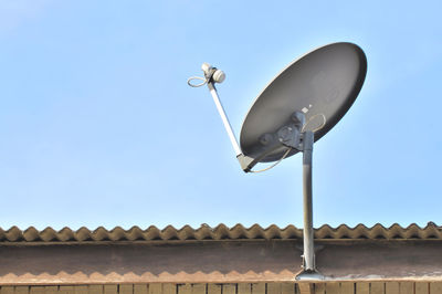 Low angle view of satellite dish on roof against clear blue sky