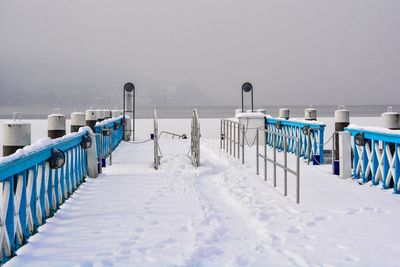 Snow covered field by railing during winter
