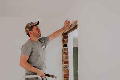 A young caucasian male builder clears a doorway using a crowbar.