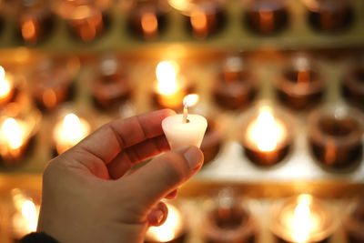 Close-up of hand holding lit candles