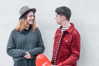 Portrait of a smiling young woman against wall