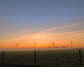 Beautiful and slightly misty sunrise behind the windmills which begins to light up the landscape