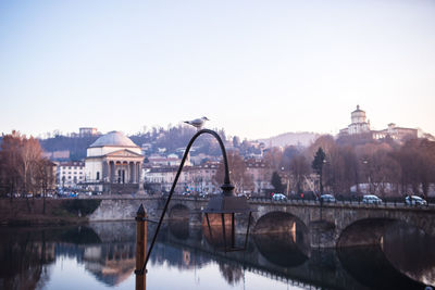 Arch bridge over river against buildings in city