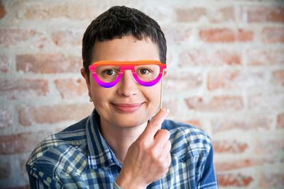 Portrait of smiling woman holding sunglasses prop