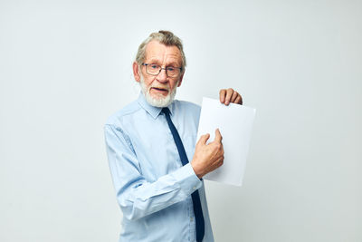 Portrait of businessman holding paper against white background