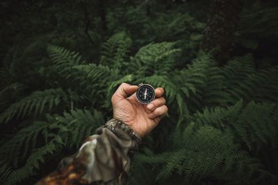 Close up of explorer male holding a compass in green rainy forest.survival travel,lifestyle concept
