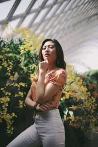 Low angle view of beautiful woman standing by flowering plants in park