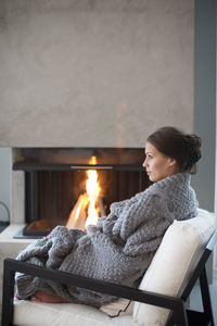 Young woman sitting in front of fireplace