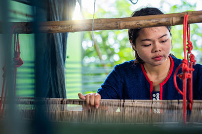 Young woman weaving loom in workshop