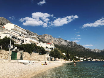 Buildings by sea against sky