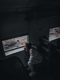 Side view of man standing by window