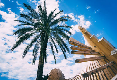 A palm tree with wooden structure in front and blue sky in the background.