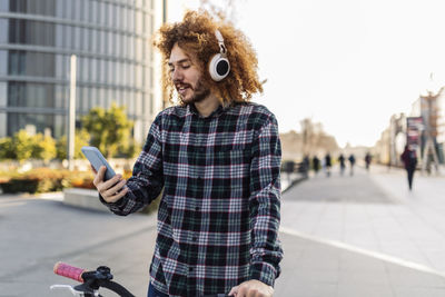 Redhead man using smart phone in front of building