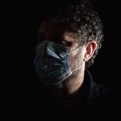 Moody portrait of an adult male person wearing a surgical mask for protection from the coronavirus