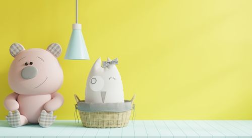 Close-up of stuffed toys against yellow wall