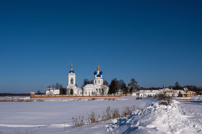 Church by building against clear blue sky during winter