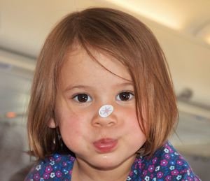 Close-up portrait of cute girl with sticker on nose