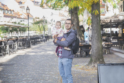 Young dad with a charming daughter in his arms in ljubljana