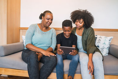 Family using digital tablet while sitting on sofa at home