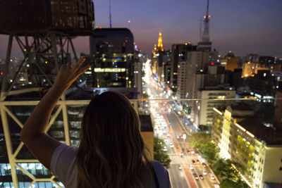 Rear view of woman against illuminated buildings in city at night