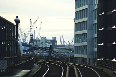 Railroad tracks amidst buildings in city against sky