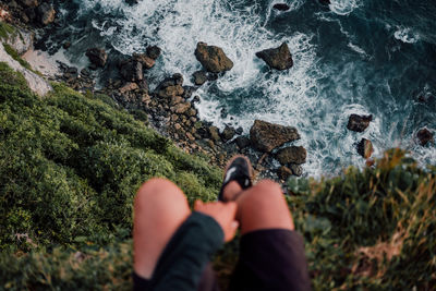 Low section of person on rock by sea