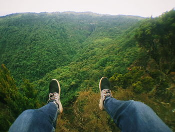 Low section of man on mountain against sky